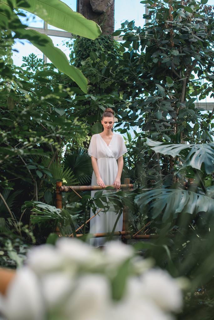 atrakcyjna kobieta w białej sukni pozowanie w tropikalnym ogrodzie - Zdjęcie, obraz