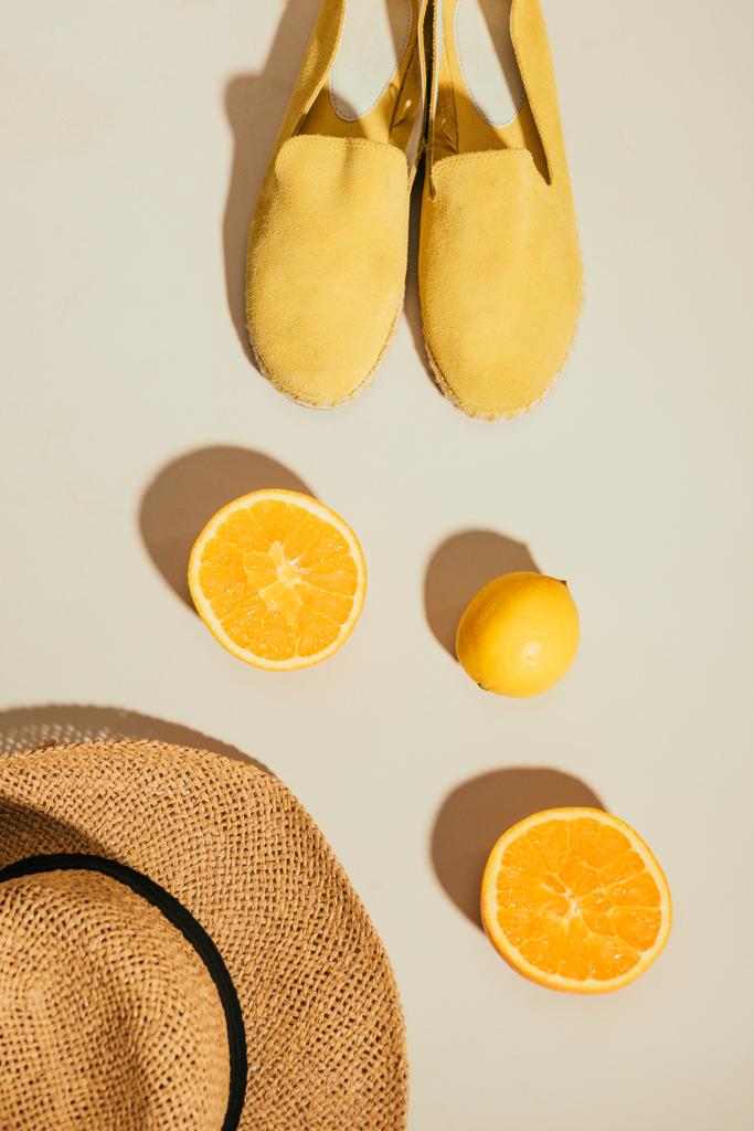 вид сверху на соломенную шляпу, лимон, оранжевые ломтики и желтые стильные эспадрильи
 - Фото, изображение