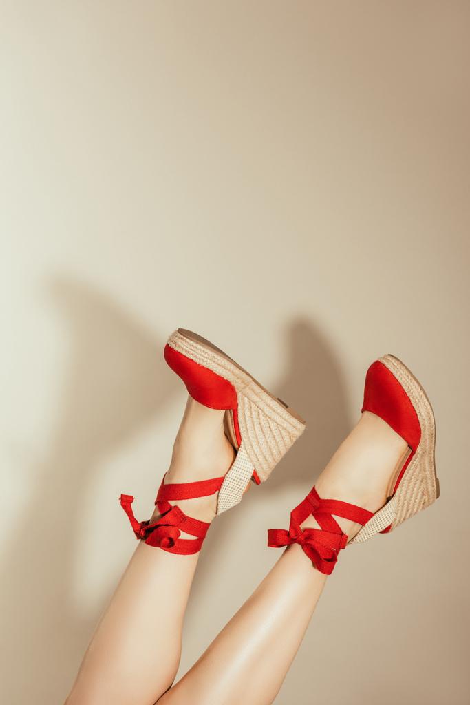 cropped shot of upside down female legs in stylish red platform sandals on beige background - Photo, Image
