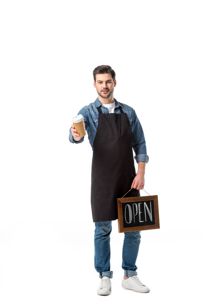 jonge ober in schort met open blackboard en koffie gaan geïsoleerd op wit - Foto, afbeelding