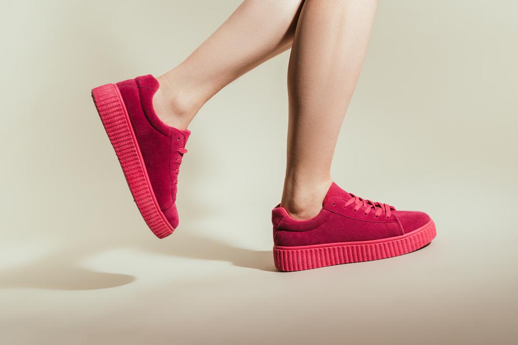 bijgesneden schot voor vrouw feet in stijlvolle stijlvolle sneakers op witte achtergrond - Foto, afbeelding