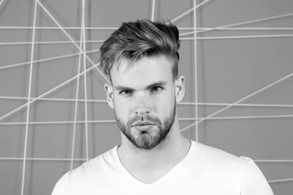Bearded man with blond hair and haircut. Macho with beard on unshaven face. Handsome guy with healthy young skin face. Hair care in salon or barbershop. Mens beauty and skincare, black and white - Photo, Image