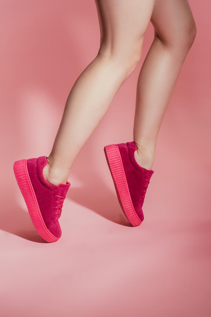 imagen recortada de chica en zapatillas de deporte con estilo de pie en los dedos de los pies sobre fondo rosa
 - Foto, Imagen
