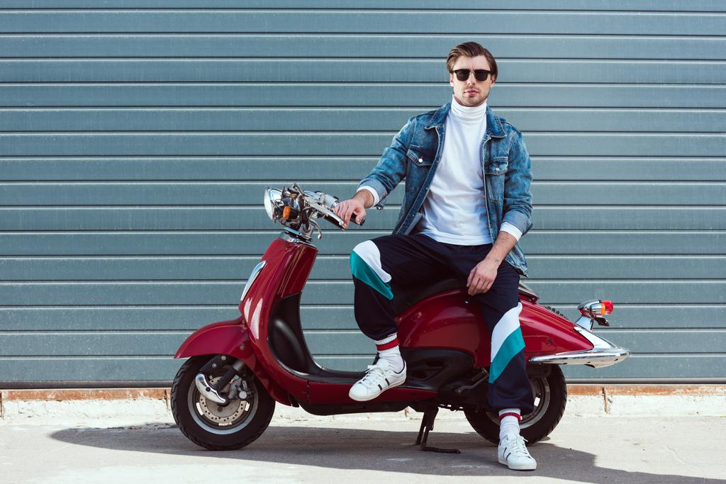 Красивый молодой человек в стильной старой школьной одежде на винтажном красном скутере
 - Фото, изображение