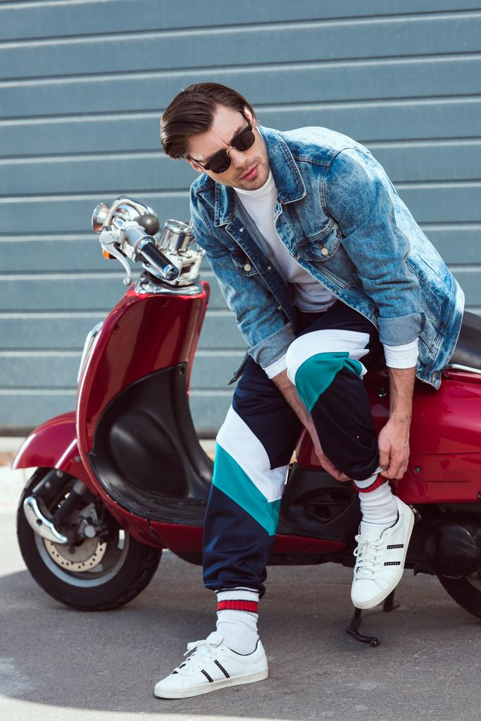 молодой человек в стильной джинсовой куртке с винтажным скутером
 - Фото, изображение