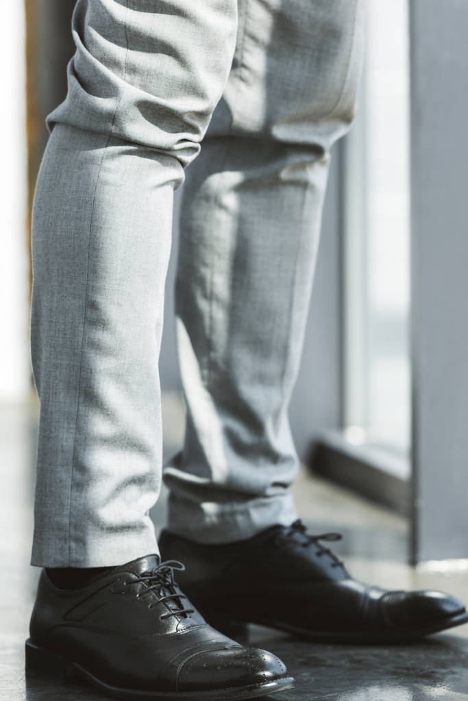 low section of businessman standing in fashionable leather shoes and pants - Photo, Image