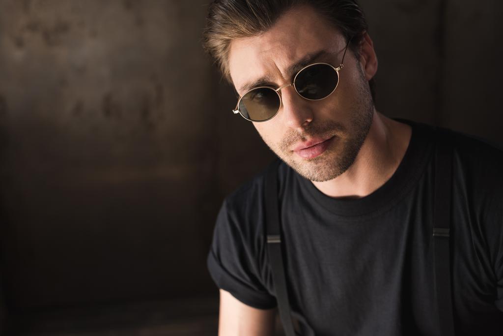 close-up portrait of handsome young man in black t-shirt and sunglasses looking at camera - Photo, Image