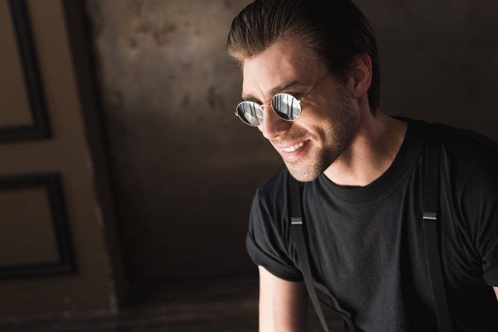 retrato de cerca del joven sonriente en camiseta negra y gafas de sol
 - Foto, Imagen