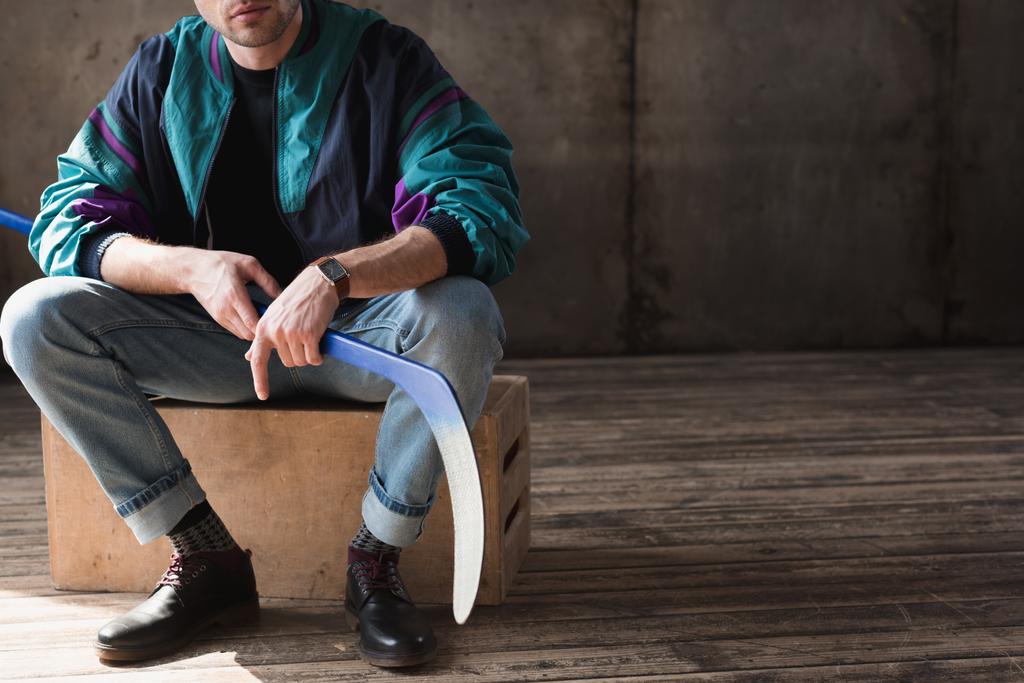 cropped shot of man in vintage windcheater with hockey stick sitting on wooden box - Photo, Image