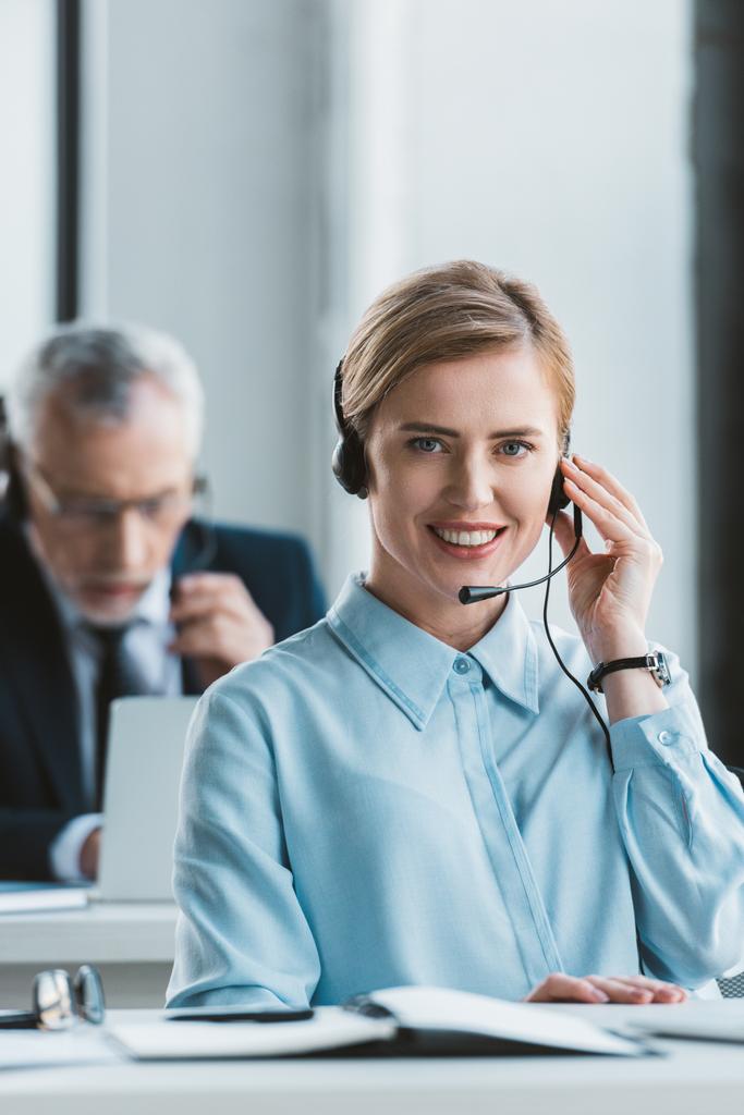 beautiful businesswoman using headset and smiling at camera - Photo, Image
