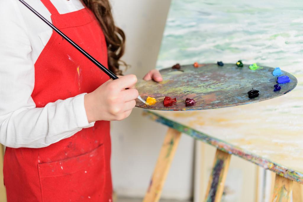 image recadrée de gamin prenant de la peinture de la palette dans l'atelier de l'école d'art
 - Photo, image