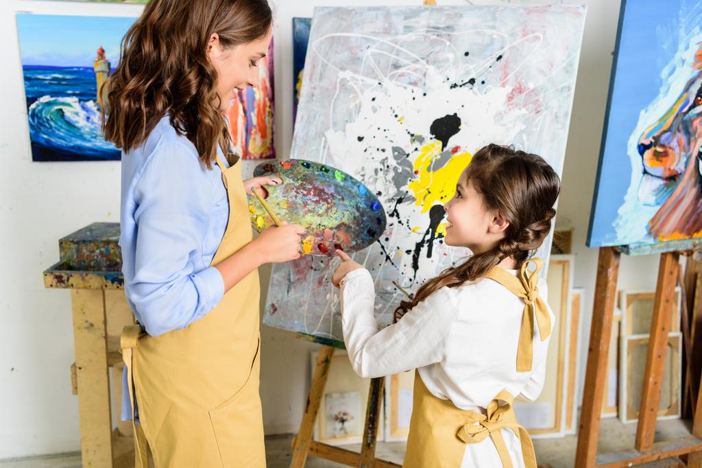 учитель и ученик выбирают краску на палитре в мастерской художественной школы
 - Фото, изображение