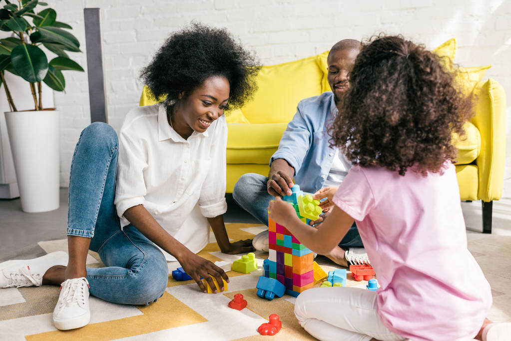 vista parziale della famiglia afro-americana che gioca con blocchi colorati insieme sul pavimento a casa
 - Foto, immagini