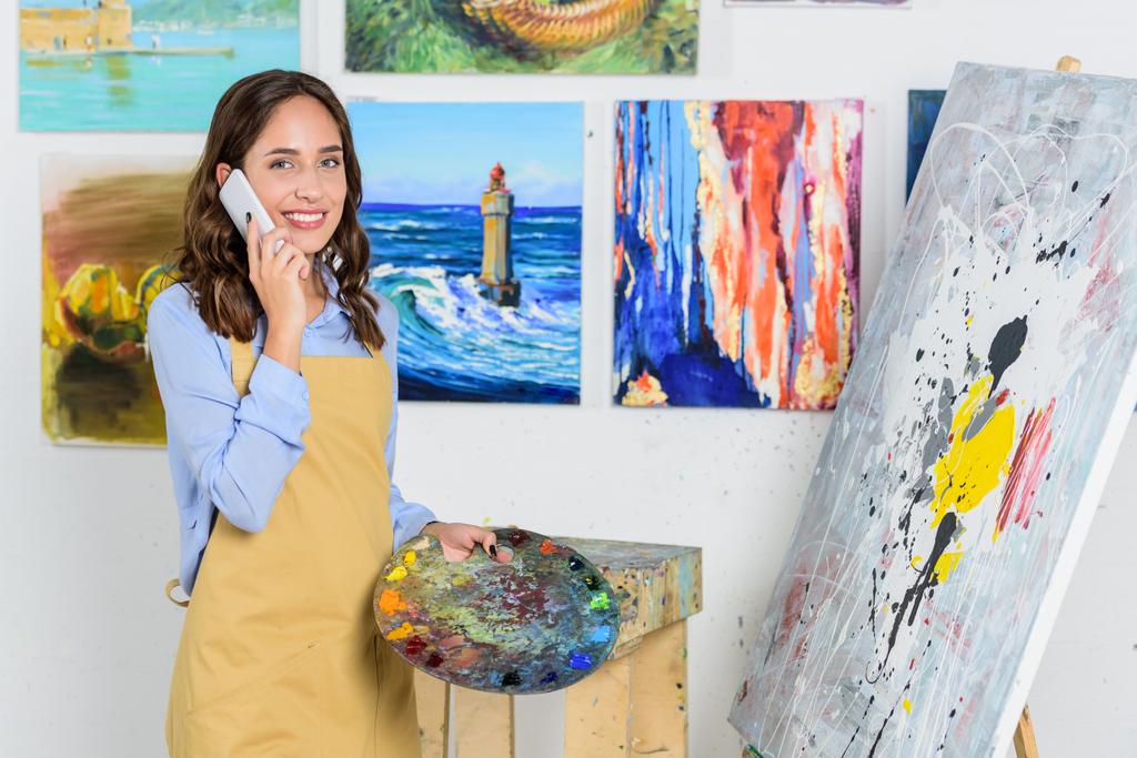 bela artista feminina falando por smartphone em oficina
 - Foto, Imagem