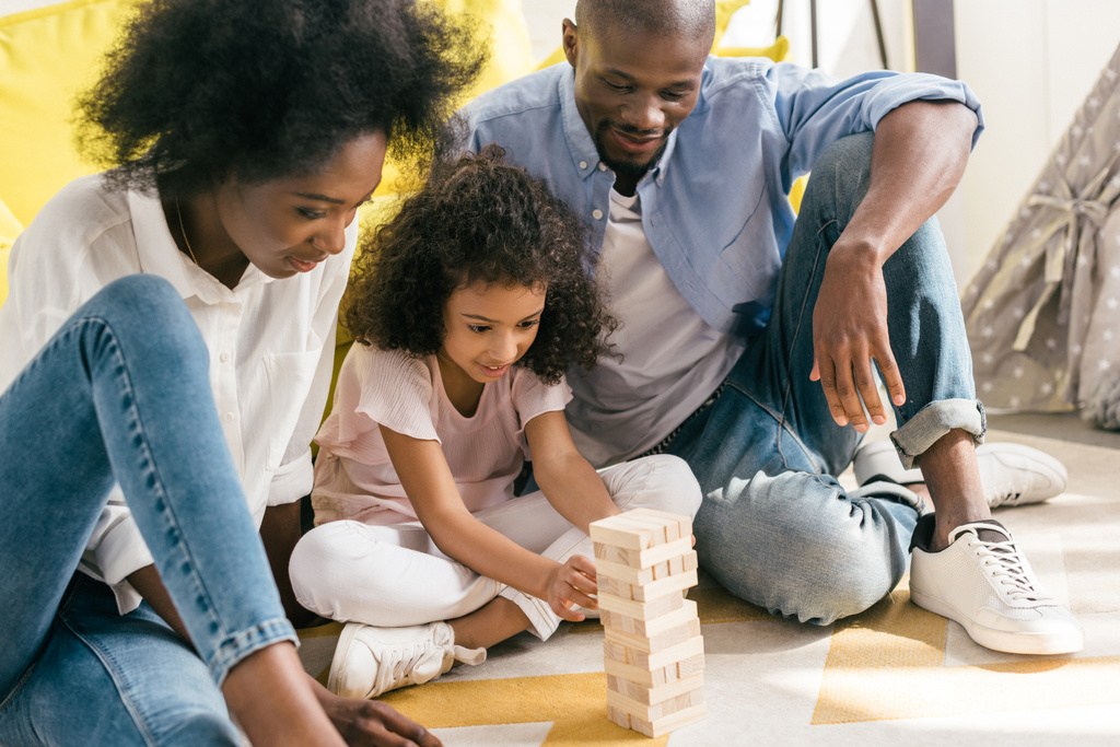 アフリカ系アメリカ人の両親と娘の演奏ブロック タワー ゲーム一緒に自宅 - 写真・画像
