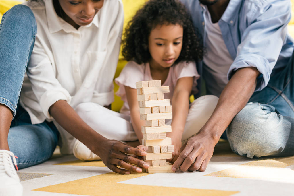 částečný pohled na africké americké rodiče a dcera hraje bloky hra věž společně doma - Fotografie, Obrázek