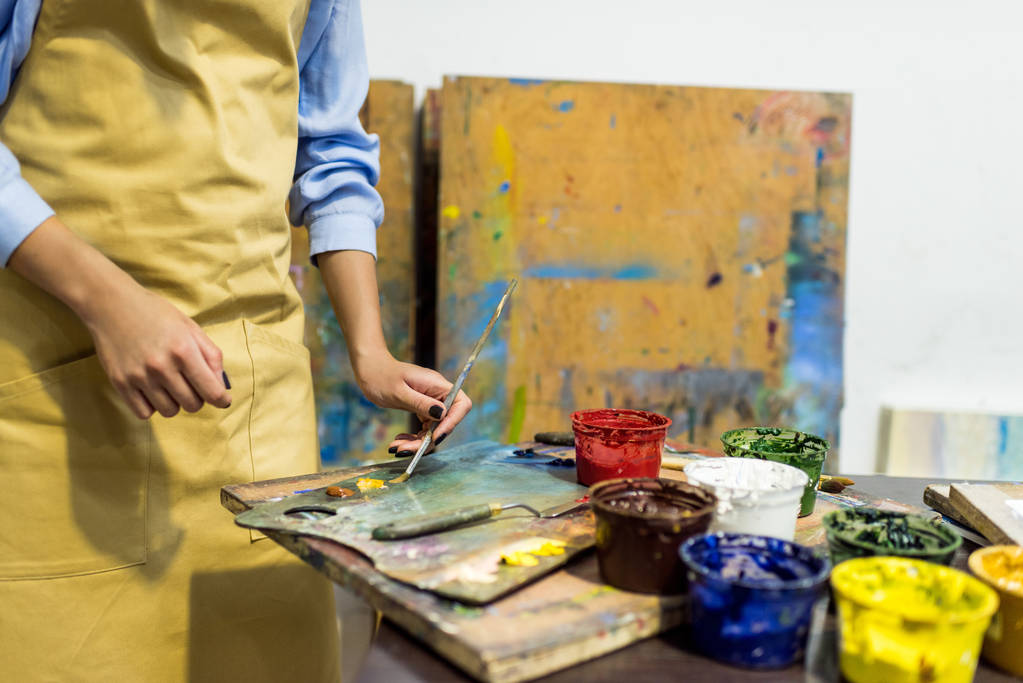 обрезанное изображение художника, взявшего краску кистью из палитры в мастерской
 - Фото, изображение