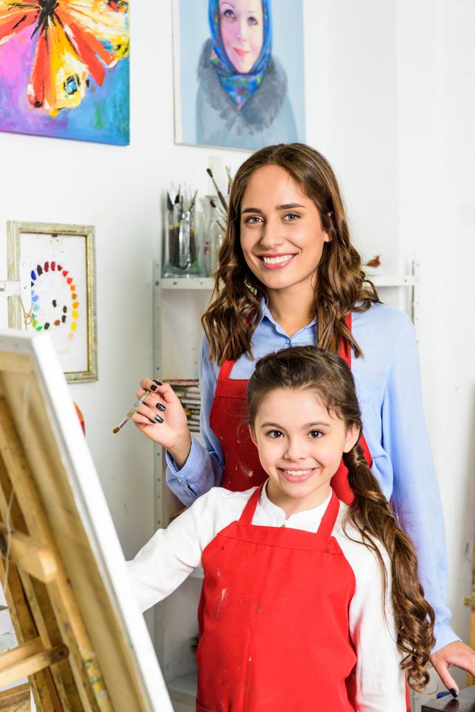 Lächelnder Lehrer und Schüler malen gemeinsam in Werkstatt der Kunstschule - Foto, Bild