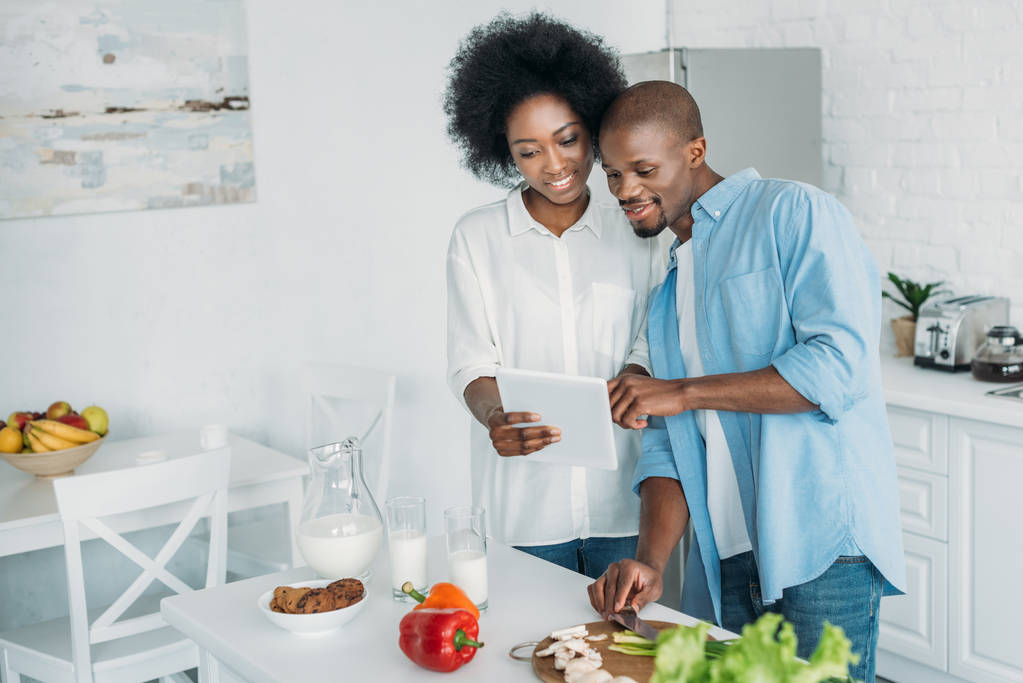 afroamericano con tavoletta e verdure fresche sul tavolo in cucina a casa
 - Foto, immagini
