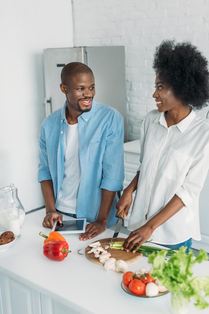 african american with tablet and fresh vegetables on table in kitchen at home - Photo, Image