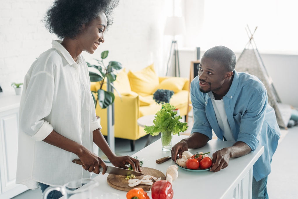 africano americano hombre mirando esposa cocina desayuno en cocina en casa
 - Foto, imagen