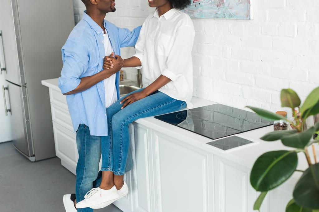 Teilansicht eines afrikanisch-amerikanischen Paares, das sich in der heimischen Küche an den Händen hält - Foto, Bild
