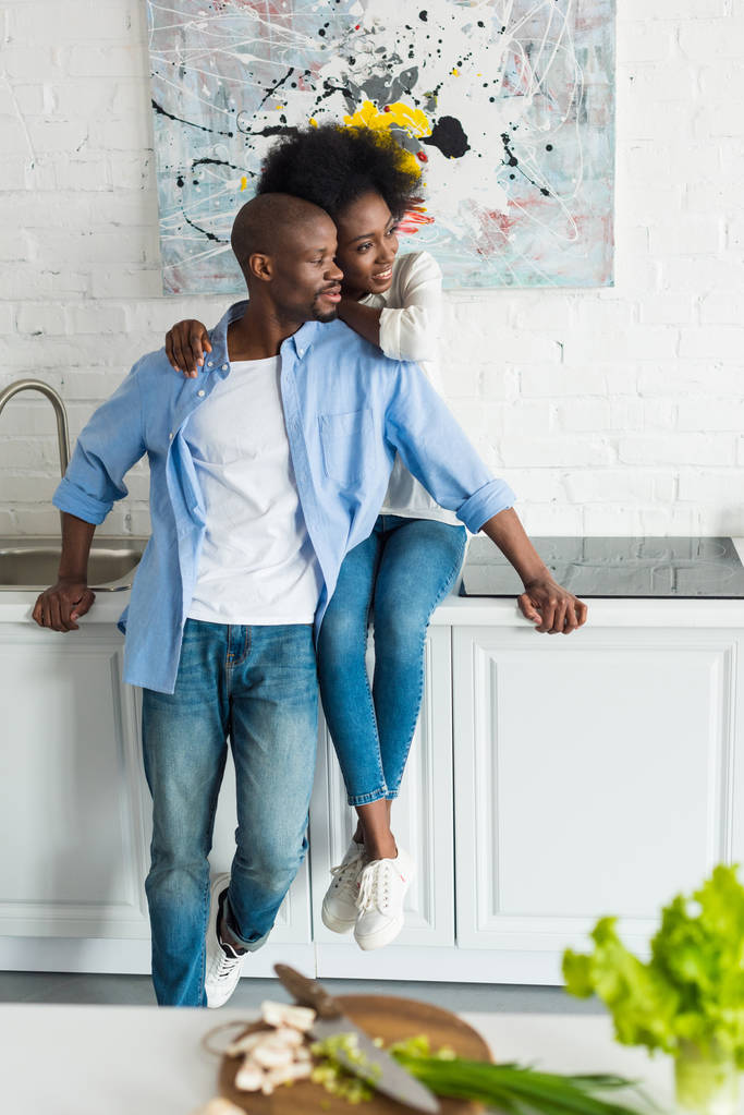 boldog afrikai-amerikai nő átölelve férje otthon a konyhában - Fotó, kép