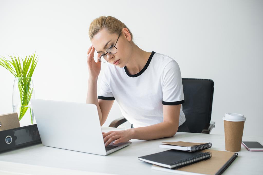 moe jonge zakenvrouw in brillen laptop gebruiken in office - Foto, afbeelding