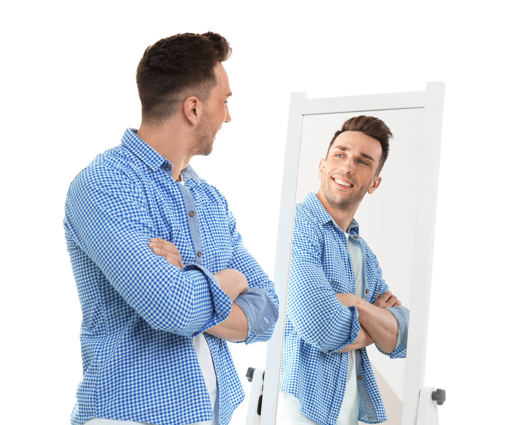Młody człowiek patrząc na siebie w lustro na białym tle - Zdjęcie, obraz