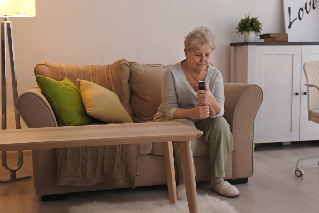 Религиозная пожилая женщина молится с Библией на диване дома
 - Фото, изображение