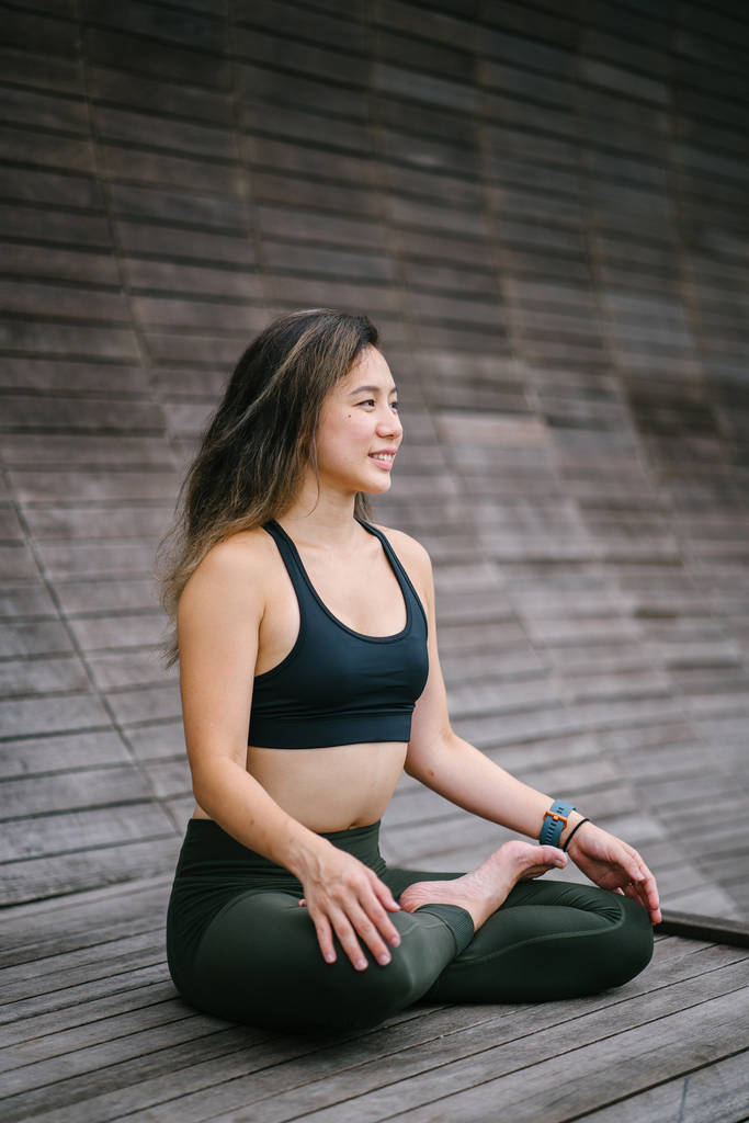 joven mujer asiática china medita en la pose de loto (una pose de yoga que es una posición de piernas cruzadas) en un parque. Ella está vestida con ropa de yoga y es tranquila w
 - Foto, Imagen