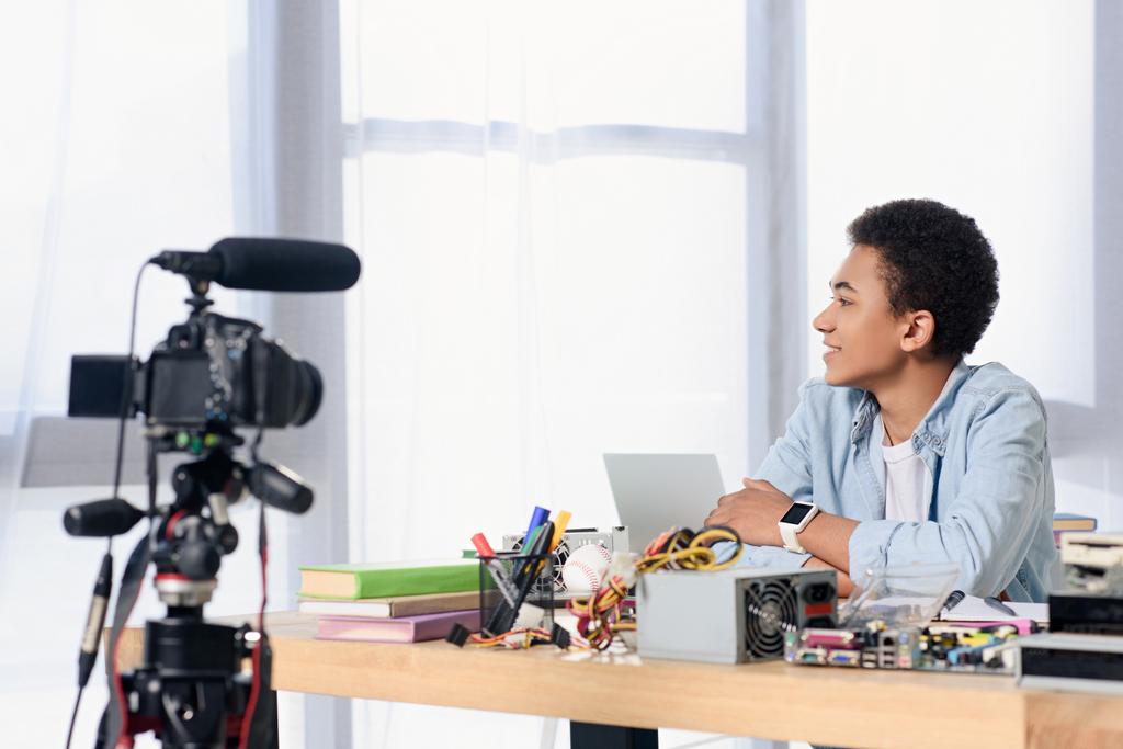 visão lateral do afro-americano adolescente atirando blog de tecnologia em casa
 - Foto, Imagem