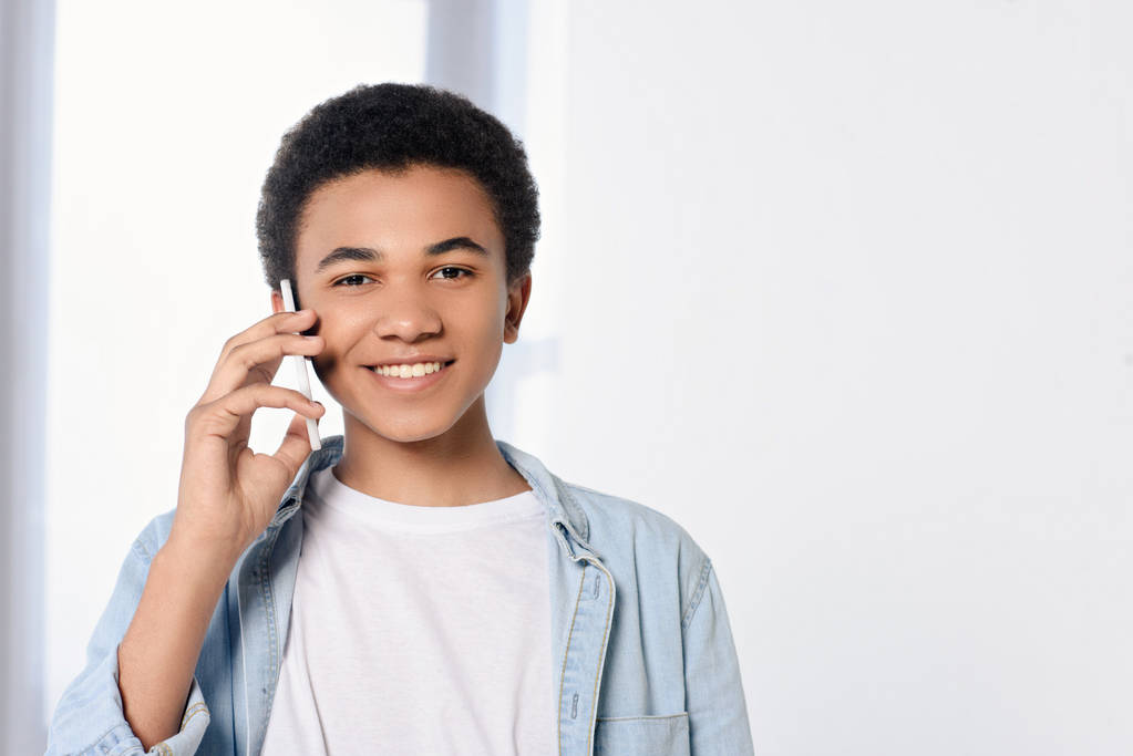 усміхнений афроамериканський підліток розмовляє по телефону вдома
 - Фото, зображення