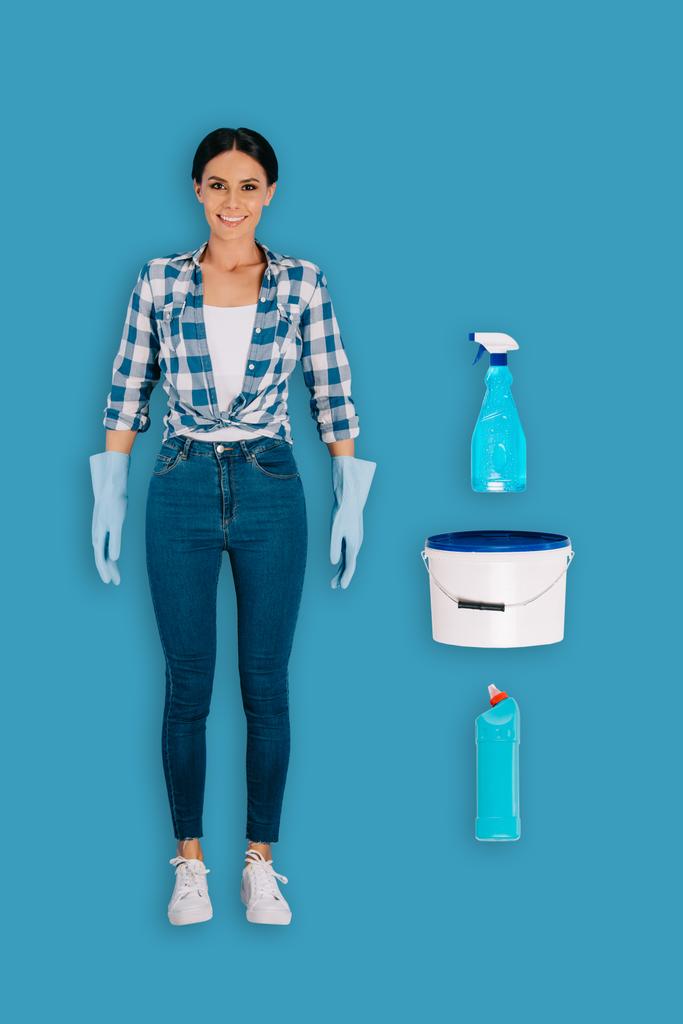 Widok z kobieta z góry sprzątaczka w rękawice ochronne z butelka spray, wiaderko i płyn do czyszczenia na białym tle na niebieskim tle - Zdjęcie, obraz