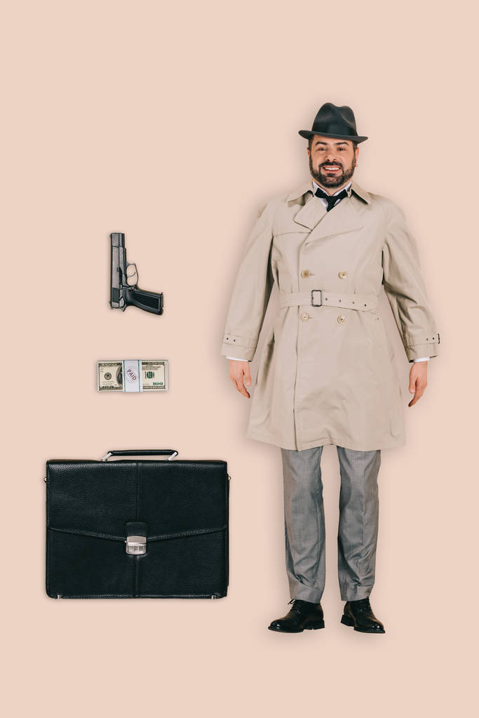 το Top view αρσενικό δολοφόνος στο καπέλο με πιστόλι, χρήματα και Χαρτοφύλακα που απομονώνονται σε ροζ φόντο - Φωτογραφία, εικόνα