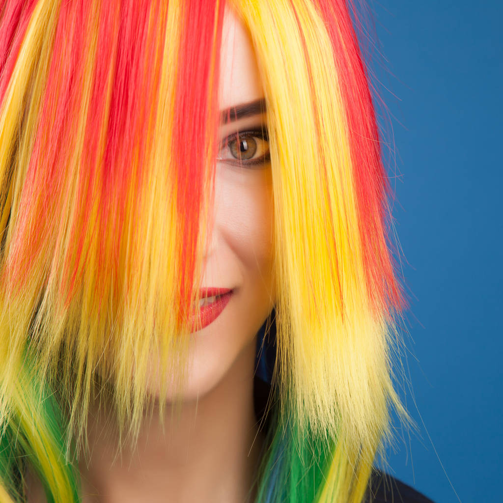 beautiful woman wearing color wig against blue background - Photo, Image