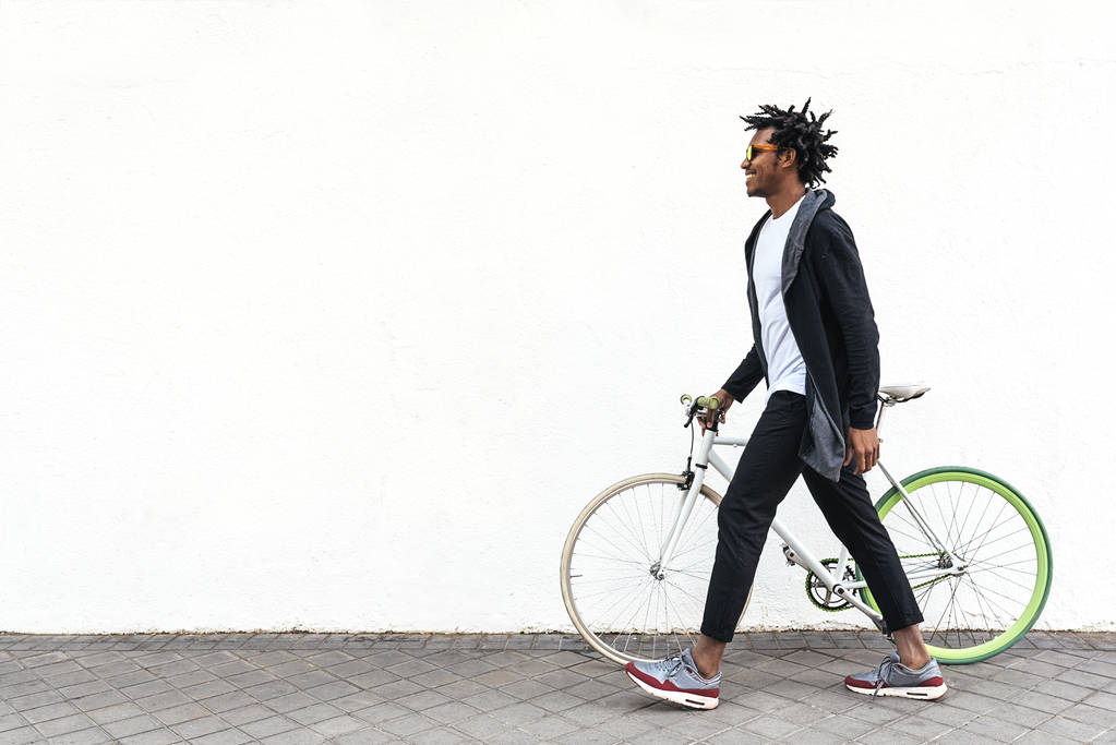 Красивый молодой человек с мобильным телефоном и велосипедом с фиксированной передачей
. - Фото, изображение