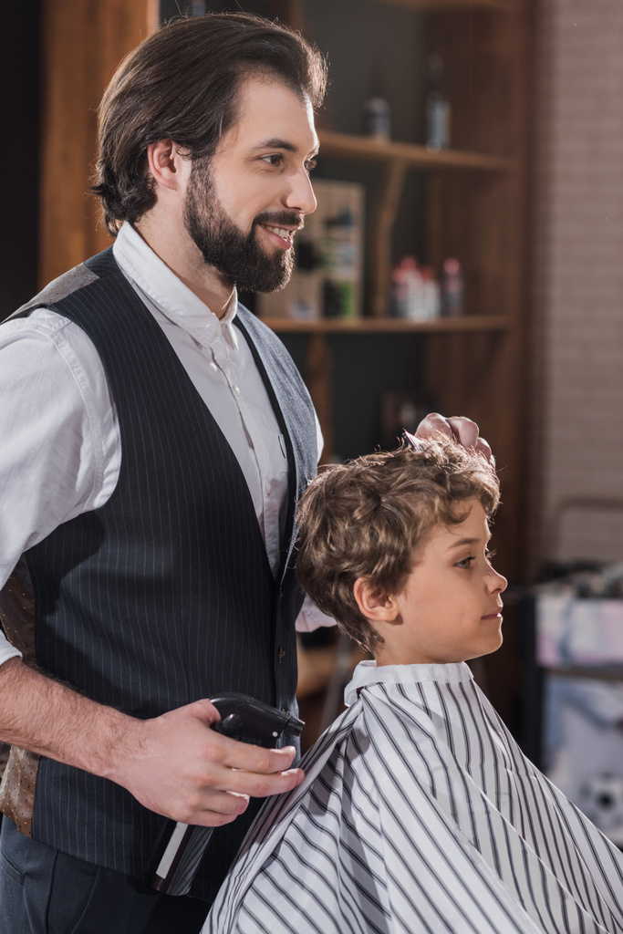 guapo barbudo peluquero peinando pelo de niño pequeño
 - Foto, imagen