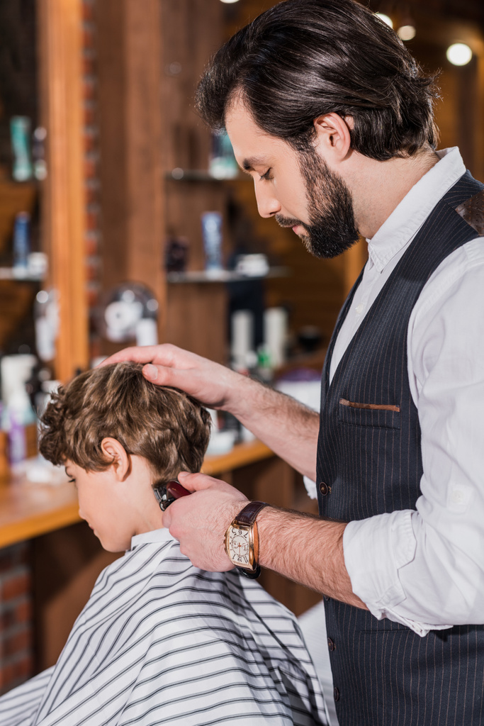 adorable enfant bouclé se faire couper les cheveux du coiffeur avec tondeuse à cheveux
 - Photo, image