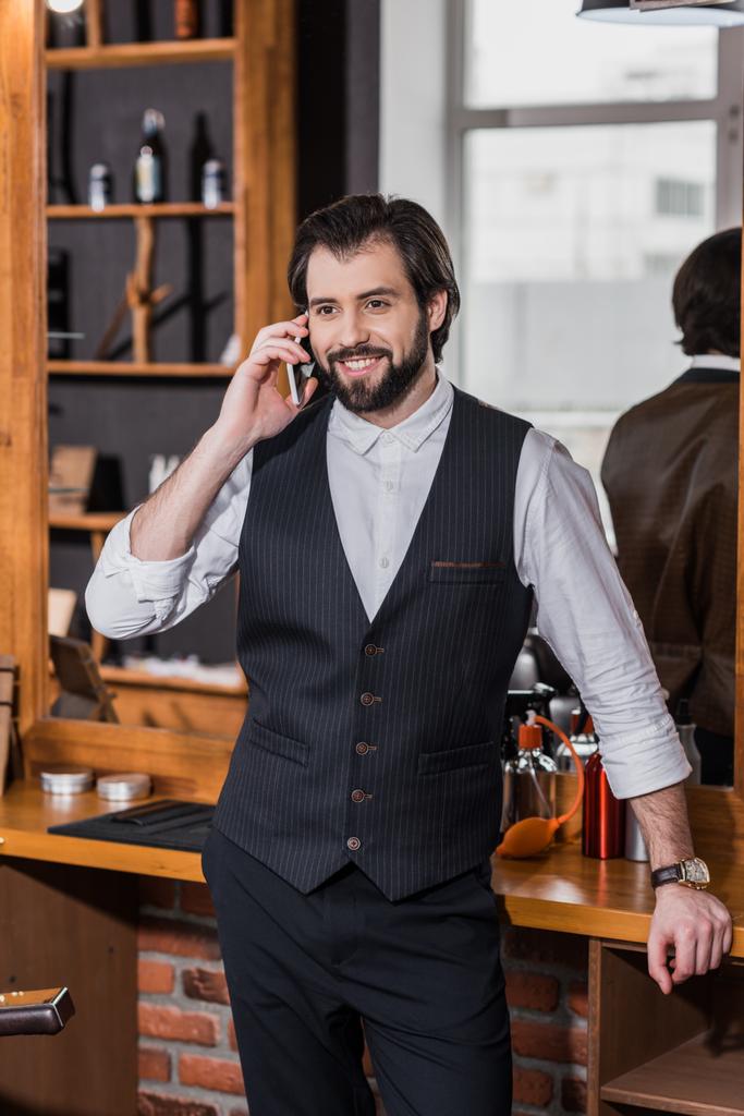 guapo joven barbero hablando por teléfono en el lugar de trabajo
 - Foto, imagen
