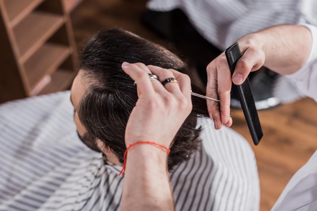 высокий угол зрения парикмахера стрижка волос клиента с ножницами
 - Фото, изображение