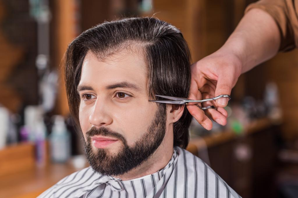 yakın çekim yakışıklı genç adam saç kesimi berber dükkanında elde kadeh - Fotoğraf, Görsel