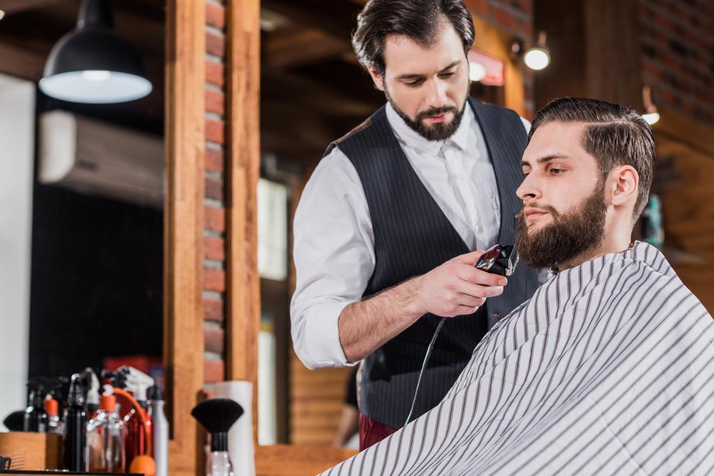yakışıklı emin Kuaför tıraş adamla saç kesme makinesi - Fotoğraf, Görsel