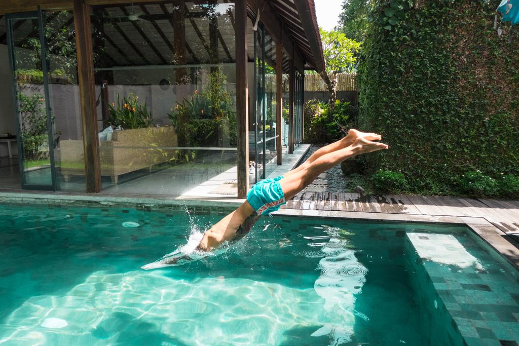 Боковой вид татуированного мужчины, ныряющего в бассейн во время отдыха на бали, индонация
 - Фото, изображение