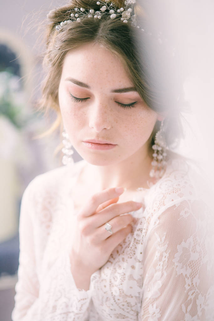 Portrait of beautiful bride. Morning of the bride. Wedding morning. Makeup. Bride with cones and fair hair. Fragile bride in white lace negligee - Photo, Image