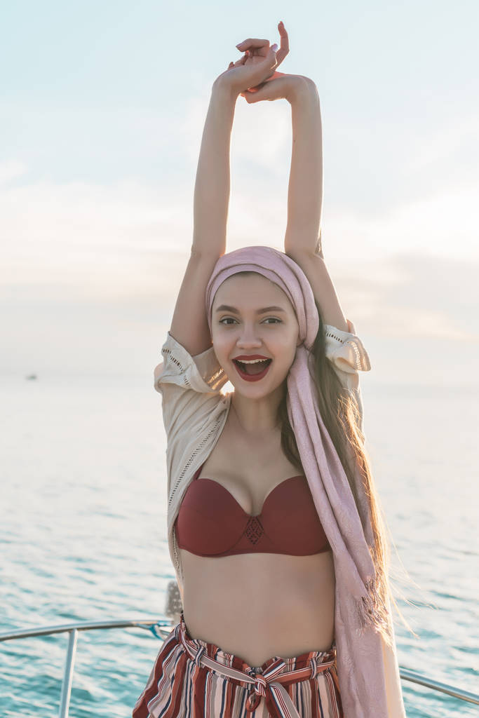 menina elegante feliz levantou as mãos para cima, alegra-se férias bem esperadas e viagem pelo mar
 - Foto, Imagem