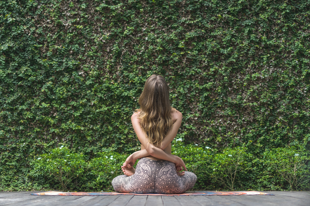 vue arrière de la femme pratiquant le yoga en pose de lotus devant le mur recouvert de feuilles vertes
 - Photo, image