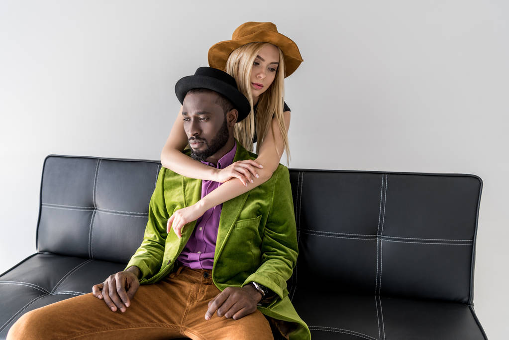 caucasian woman hugging stylish african american boyfriend on sofa isolated on grey - Photo, Image