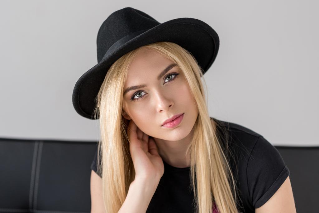 portrait of attractive woman in black hat looking at camera isolated on grey - Photo, Image