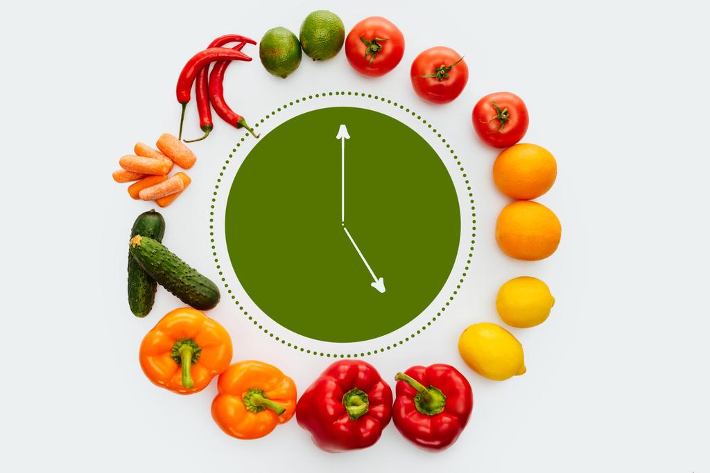κάτοψη του κύκλου από λαχανικά και φρούτα με πράσινο ρολόι μέσα σε απομονωμένα σε λευκό - Φωτογραφία, εικόνα